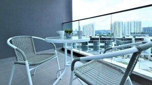 A balcony with two wicker chairs, a small round table, and a potted plant. - Executive 3 BR Condo, Cyberjaya (Cyberjaya)