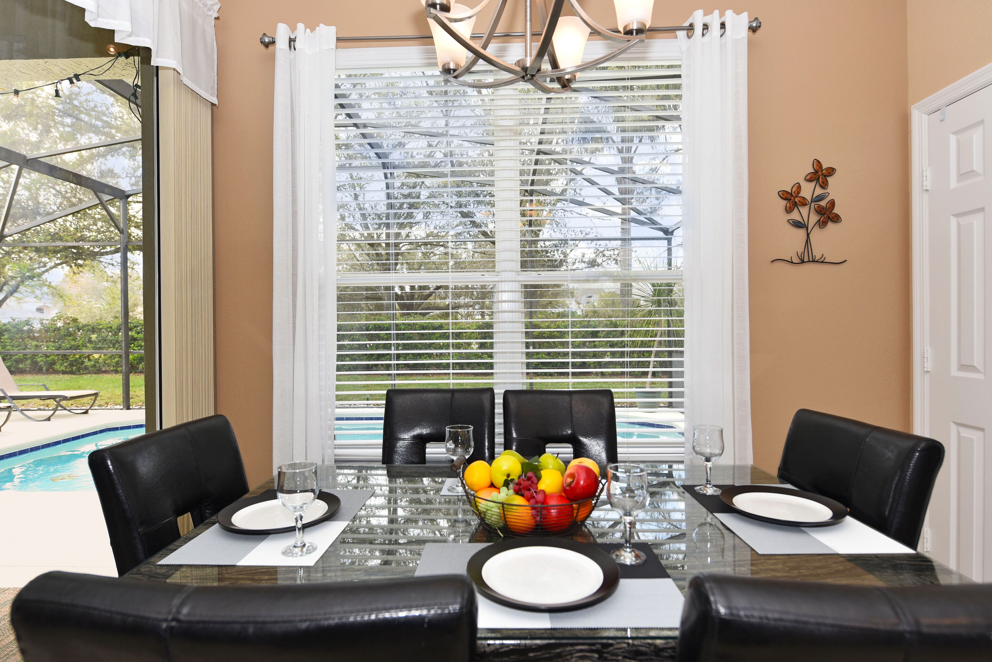 A dining area with a glass table, black chairs, and a fruit bowl.