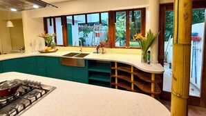 Une cuisine moderne dotée d’un plan de travail incurvé, d’une cuisinière à gaz, d’un évier et d’une fenêtre donnant sur un paysage verdoyant.