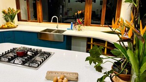 Une cuisine équipée d’une cuisinière à gaz, d’un évier et d’une fenêtre avec des stores en bois.