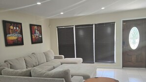 A spacious living room with a large beige sectional sofa, a round wooden coffee table, and two abstract paintings on the wall. - Home Away from Home with Gulf Access and Heated Pool (Cape Coral)