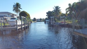 A marina with boats docked, a waterway, and palm trees.