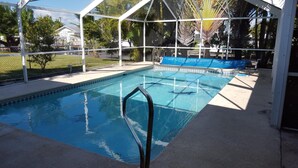 A swimming pool with a clear blue water, surrounded by a white fence and covered with a blue tarp. - Home Away from Home with Gulf Access and Heated Pool (Cape Coral)