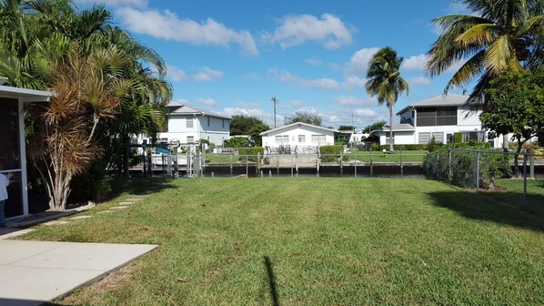 A residential area with houses, a grassy yard, and palm trees.