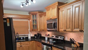 A kitchen with wooden cabinets, a stainless steel refrigerator, a microwave, and a stove. - Home Away from Home with Gulf Access and Heated Pool (Cape Coral)