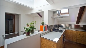 A modern kitchen with a skylight, wooden cabinets, and a microwave.