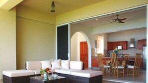 A spacious living area with a sofa set, a coffee table, and a view into the kitchen area.
