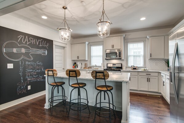 Enjoy cooking in this well-equipped kitchen with a central island, bar stools, and stainless steel appliances.