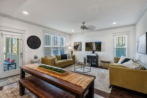 Relax in this spacious living room with a high ceiling, featuring a comfortable sofa, wooden bench, and wall-mounted TV.