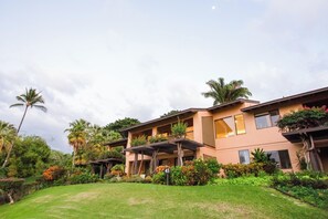 A multi-story building with balconies, surrounded by lush greenery and palm trees.