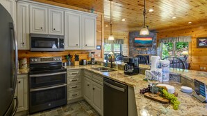 A kitchen with white cabinets, stainless steel appliances, and a granite countertop. - Gatlinburg, Hot Tub, Huge Arcade, Dual Racing, Theater, Walk-2-Pool, Free Tix (Gatlinburg)