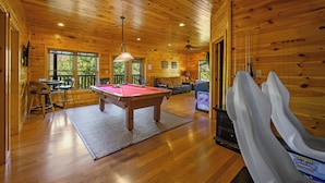 A wooden cabin interior with a pool table, seating area, and arcade machines. - Gatlinburg, Hot Tub, Huge Arcade, Dual Racing, Theater, Walk-2-Pool, Free Tix (Gatlinburg)