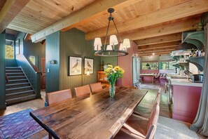 Un'ampia sala da pranzo con un tavolo e sedie in legno, un vaso con fiori e una scala che conduce a un altro livello.