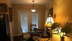 A dining area with a wooden table, chairs, a glass-top table, a lamp, and a vase with flowers. - Awesome condo, great location, quiet area, completely updated, with wifi.& AC (Ruidoso)