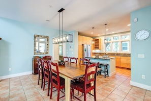 Un comedor amplio con una mesa de madera y sillas rojas, una cocina con una isla grande y un reloj en la pared.