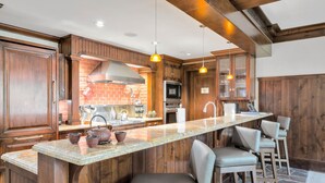 A kitchen with wooden cabinets, a granite countertop, and a built-in oven. There are two pendant lights hanging above the island. - One Willow Bridge Road - 3-room residence (Vail)