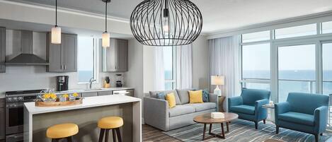 Habitación de hotel moderna con cocina, comedor y un conjunto de sofás.