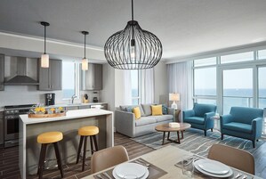 Et moderne hotelværelse med tekøkken, spiseplads og sofaarrangement.
