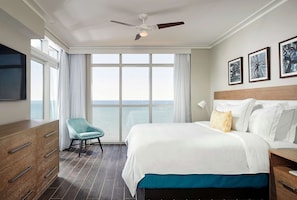 A hotel room with a bed, a chair, a dresser, and a ceiling fan.