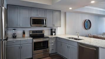 A modern kitchen with stainless steel appliances, grey cabinetry, and a granite countertop.