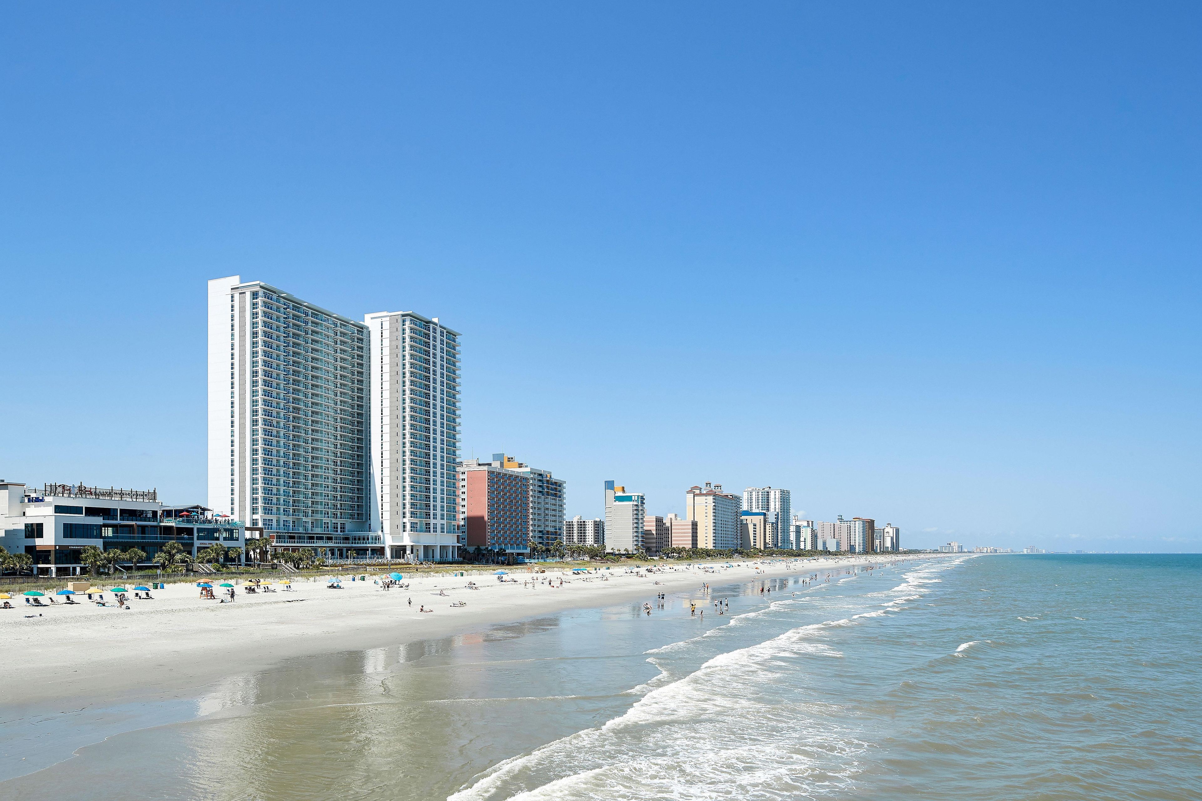 A beachfront hotel with multiple high-rise buildings, a sandy beach, and the ocean.