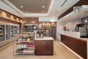 Un espacio comercial moderno con vitrinas refrigeradas, estantes llenos de bocadillos, salsas y bebidas embotelladas.