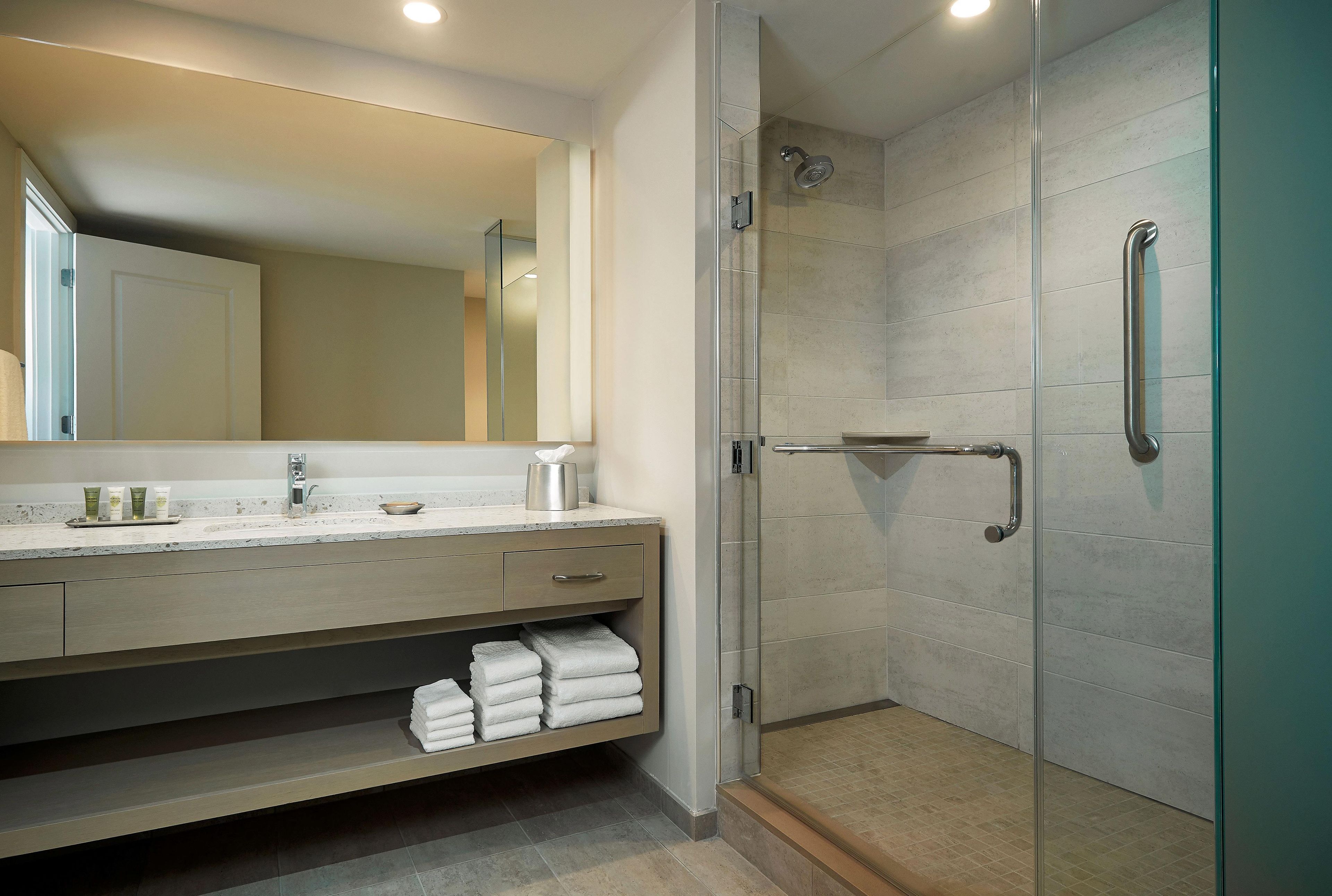 A modern bathroom with a glass shower enclosure, a vanity with a mirror, and a towel rack.