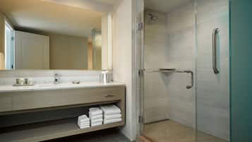 A modern bathroom with a glass shower enclosure, a vanity with a mirror, and a towel rack.
