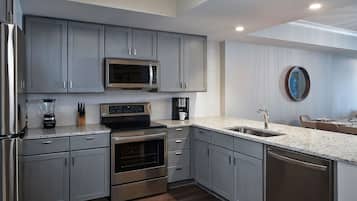 A modern kitchen with grey cabinets, stainless steel appliances, and a granite countertop.