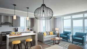 A modern hotel room with a kitchen, dining area, and seating space.
