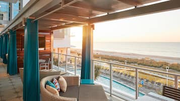 A balcony with a view of the beach and a pool.