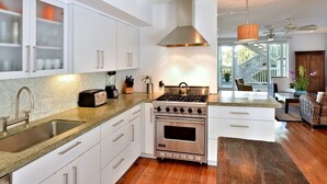 Una cocina moderna con armarios blancos, una estufa de acero inoxidable y una isla grande.