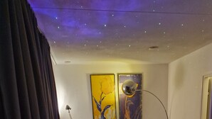 Ein modernes Wohnzimmer mit einem Kuhfellteppich, zwei Sesseln, einem Beistelltisch und einer Stehlampe.