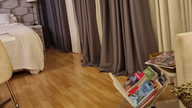 Ein Hotelzimmer mit einem Bett, einem Schreibtisch mit Zeitschriften und Vorhängen.