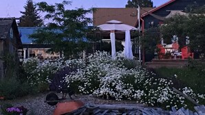 Un jardín con flores blancas, un banco de madera y una parrilla para barbacoa.