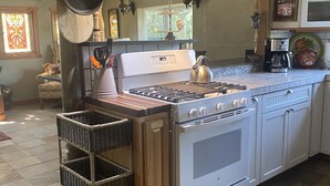 Una cocina con estufa a gas, horno y cafetera.