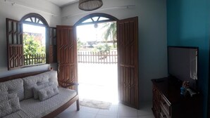 Una habitación con sofá, televisión y vista a un patio trasero cercado.