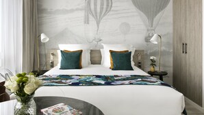 A hotel room with a bed, a nightstand, a lamp, a vase with flowers, and a wall mural of hot air balloons. - Citadines Confluent Nantes (Nantes)