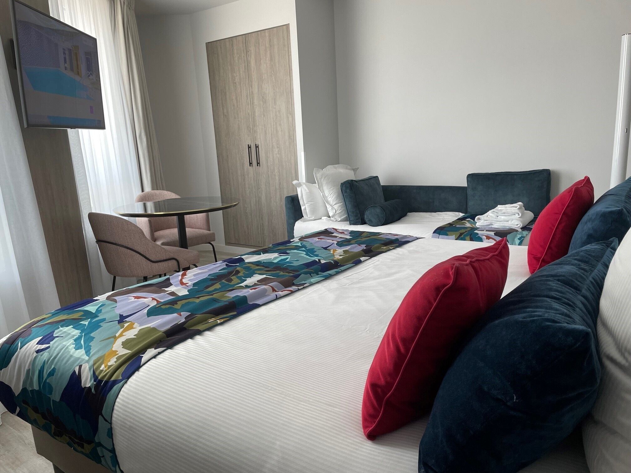 A hotel room with a bed, a desk, a chair, and a wardrobe.
