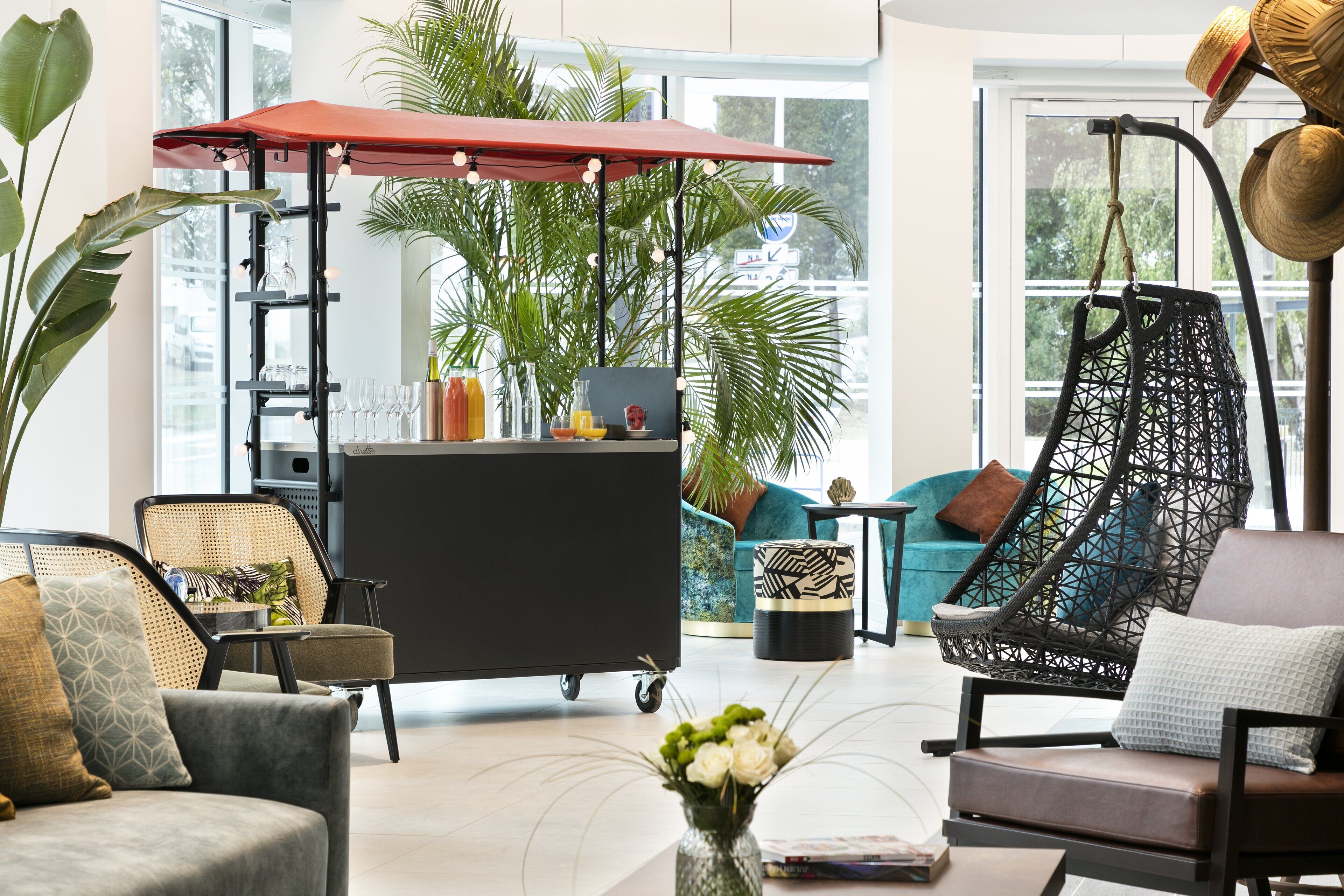 A modern living room with a sofa, chairs, a coffee table, a red umbrella, a plant, and a hanging chair.