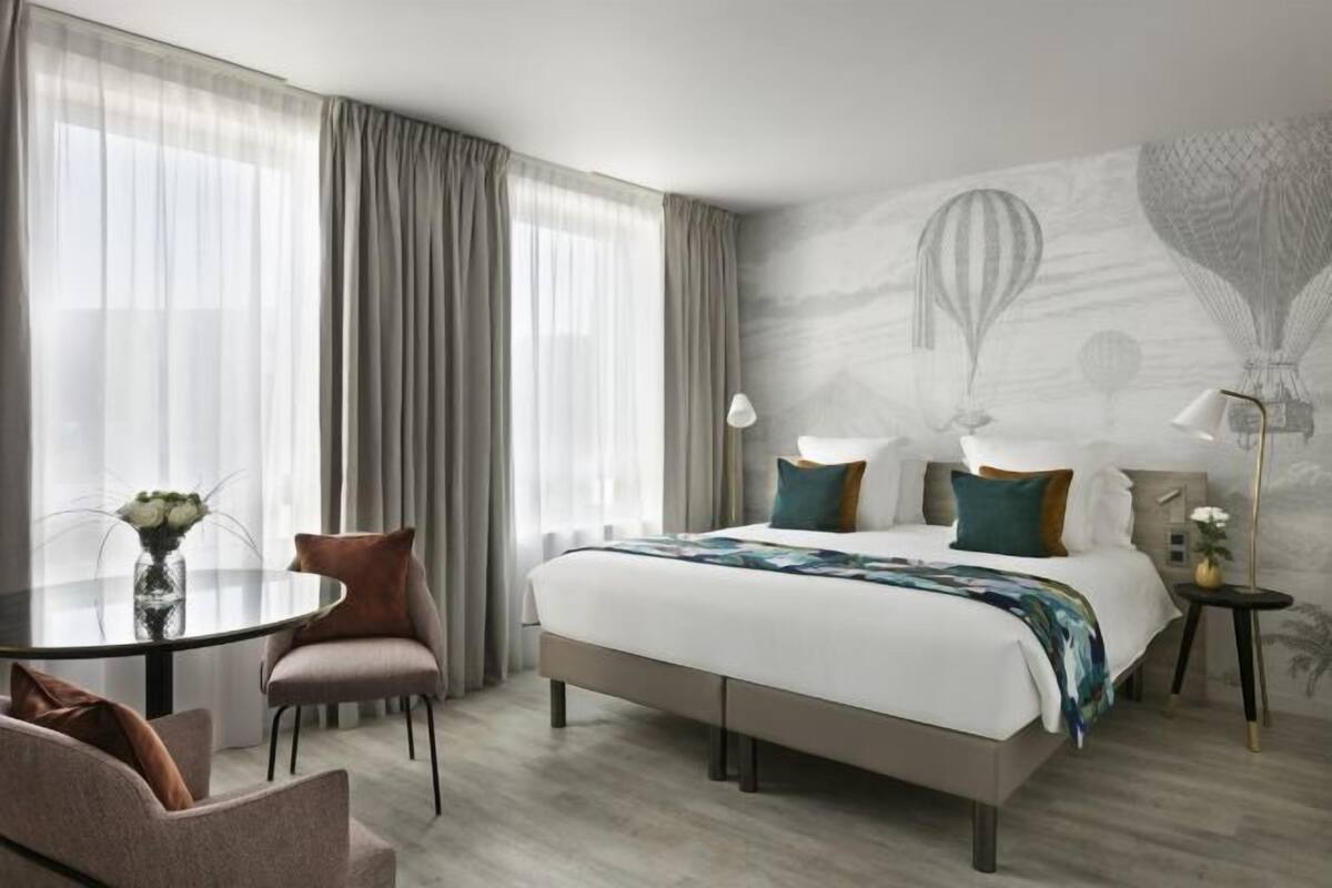 A hotel room with a bed, a round table, and a chair.