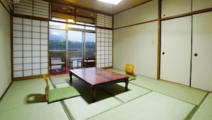 Ein traditioneller japanischer Raum mit Tatami-Bodenbelag, einem niedrigen Tisch, einem Stuhl und Schiebetüren.