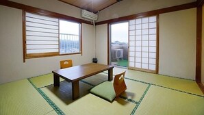 Ein traditioneller japanischer Raum mit Tatami-Boden, einem niedrigen Tisch und Schiebetüren.