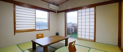 A traditional Japanese room with tatami flooring, a low table, and sliding doors.