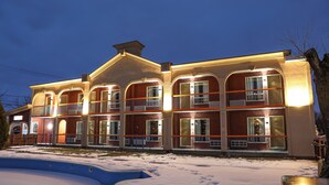 Un hotel de varios pisos con balcones, piscina y suelo cubierto de nieve.