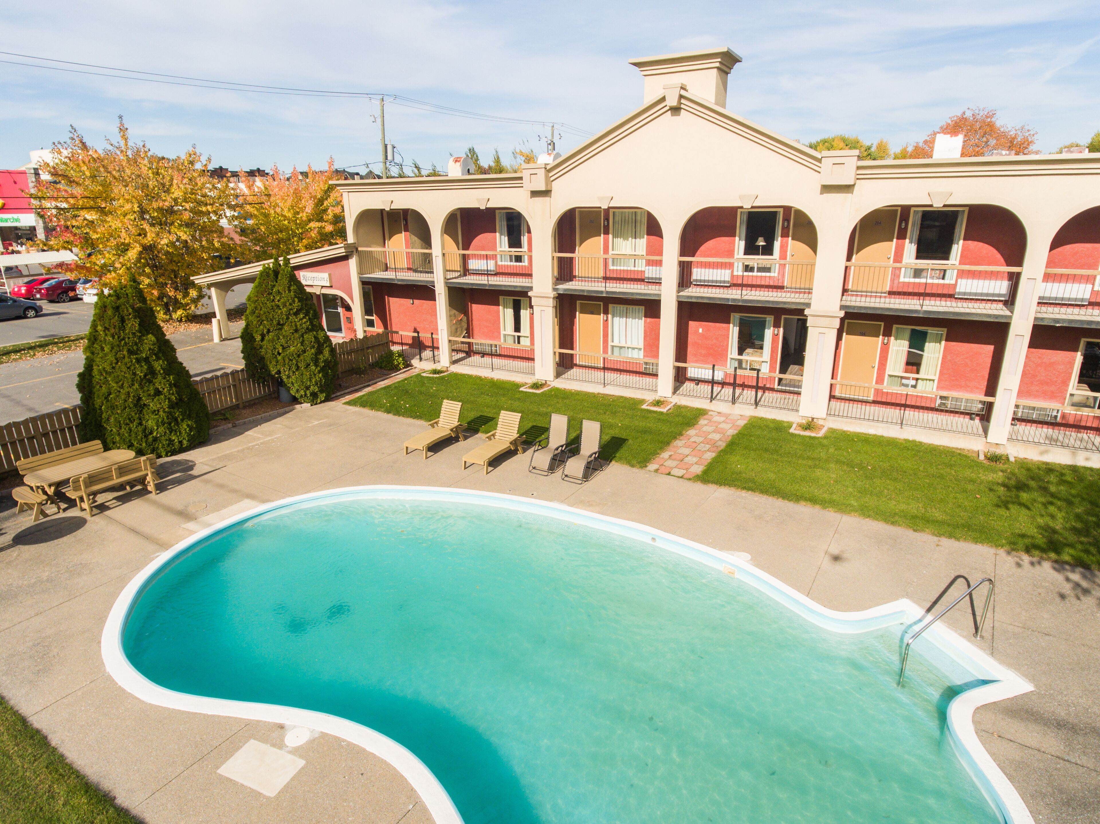 A hotel with a swimming pool, outdoor seating, and a well-maintained lawn.