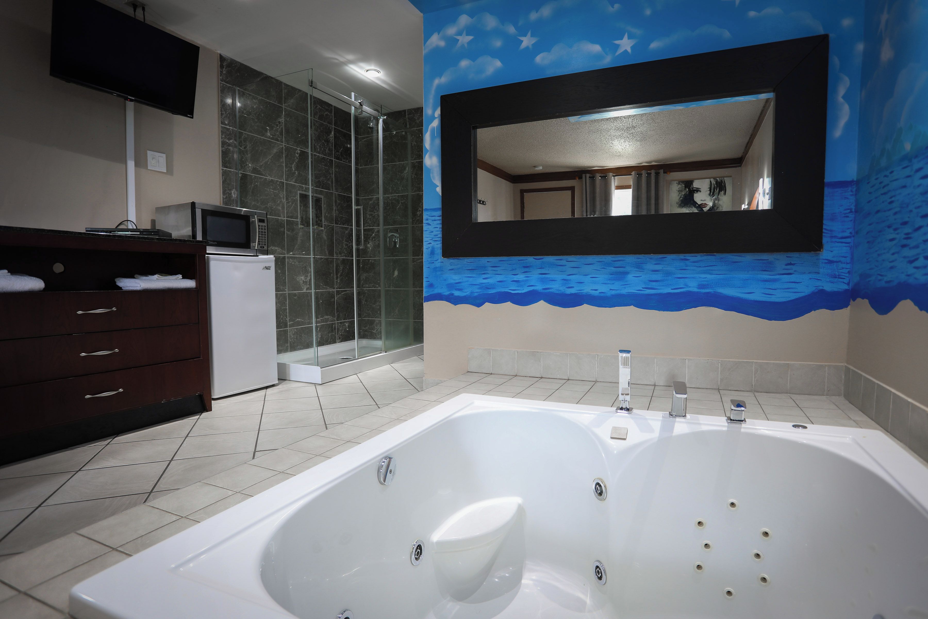 Une salle de bain moderne dotée d’une grande baignoire, d’une douche à parois de verre et d’un meuble-lavabo avec un micro-ondes.