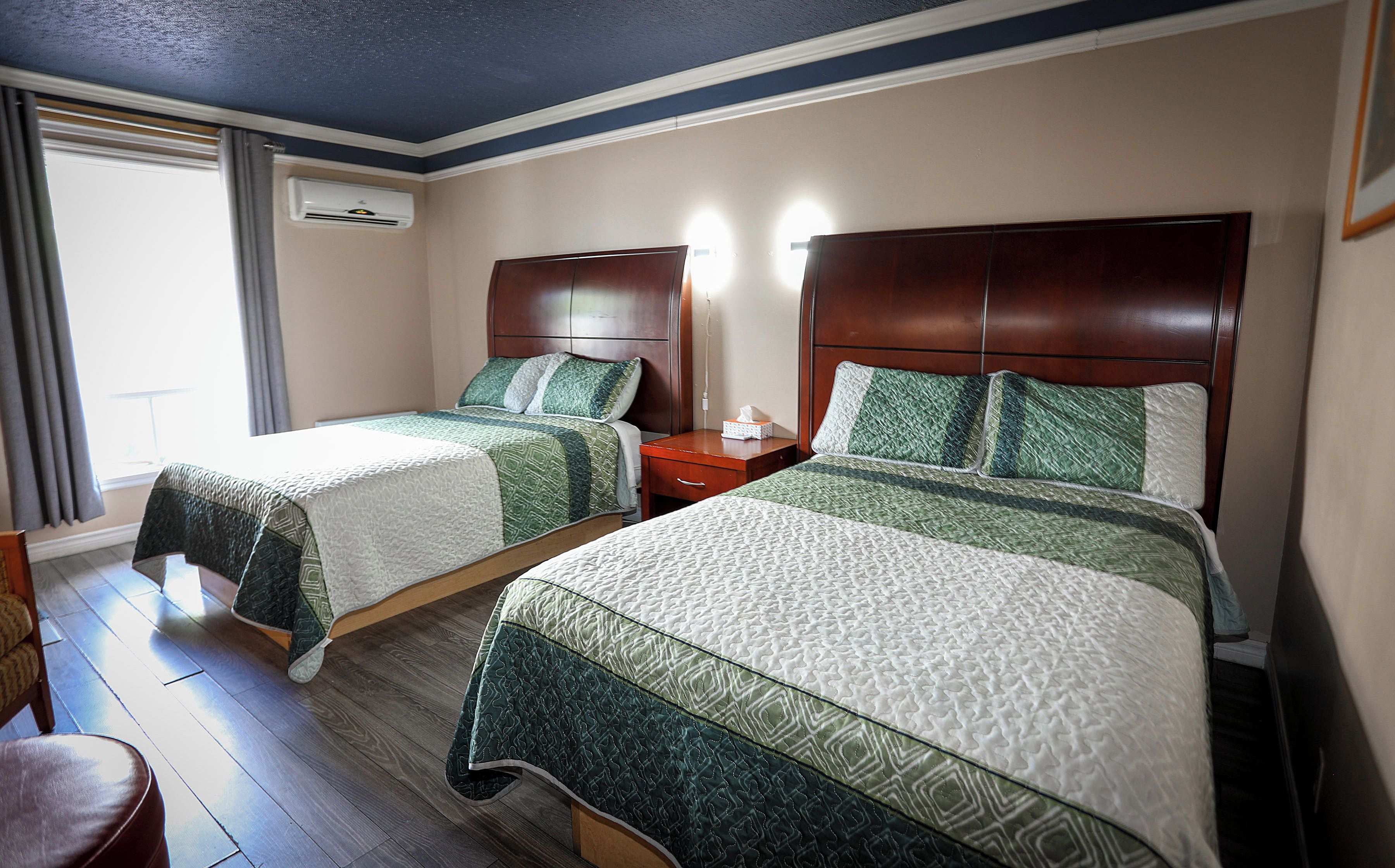 Habitación de hotel con dos camas, una mesita de noche y una ventana con cortinas.
