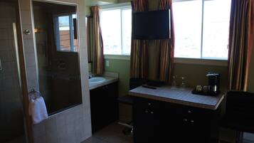 A bathroom with a glass shower door, a sink, a mirror, and a window with curtains.