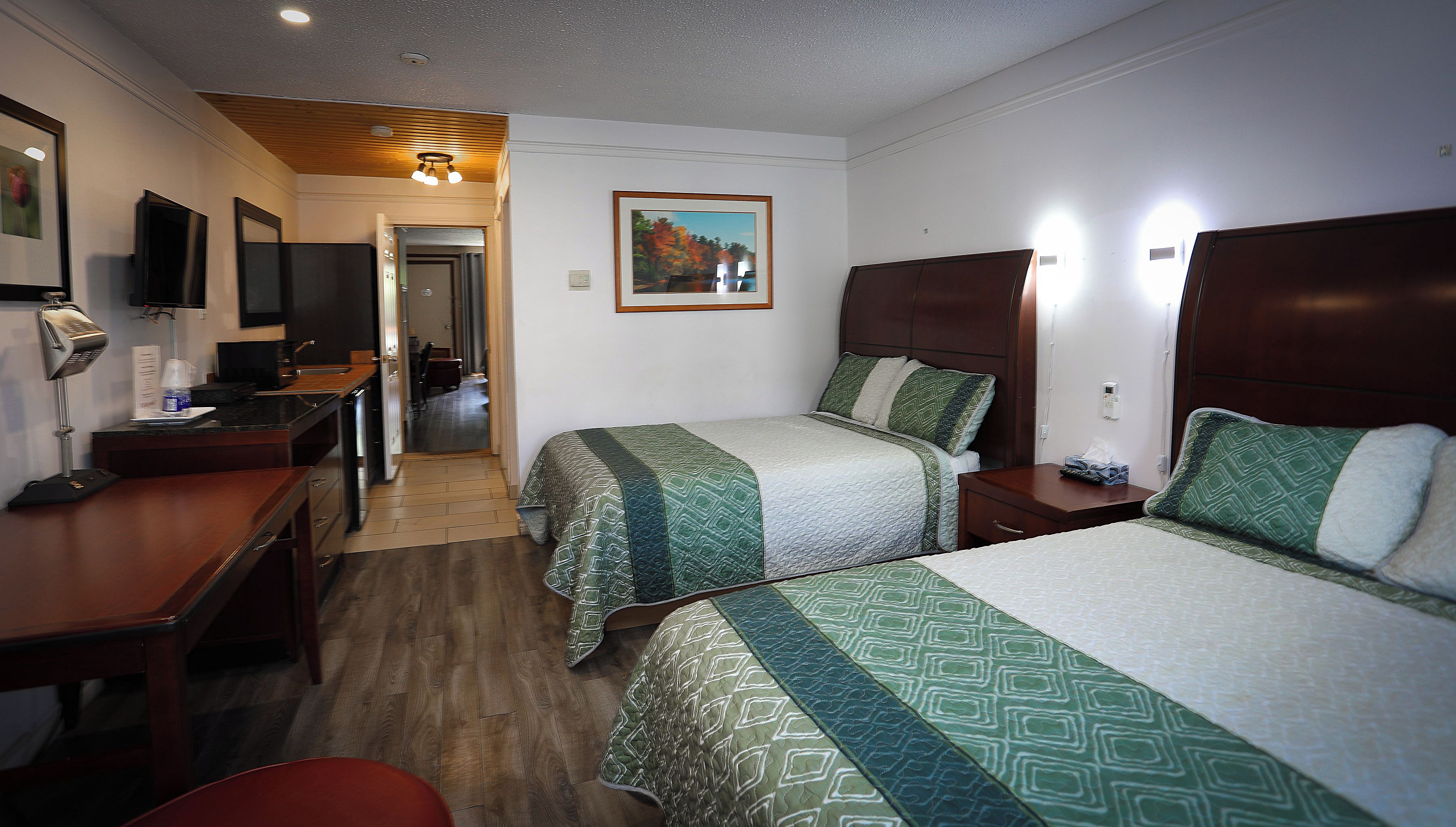 A hotel room with two beds, a desk, a chair, a television, and a painting on the wall.